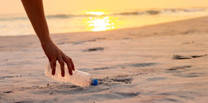 hand-woman-picking-up-plastic-bottle-cleaning-on-the-beach-volunteer-concept